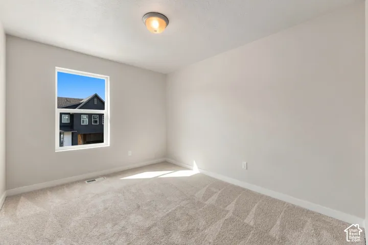 Light-colored carpeting, neutral wall paint, and a white-framed window