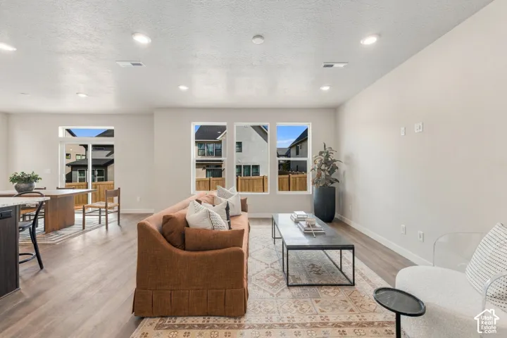 Recessed lighting, wood-finish flooring, multiple windows, light-toned walls, and an open-concept design