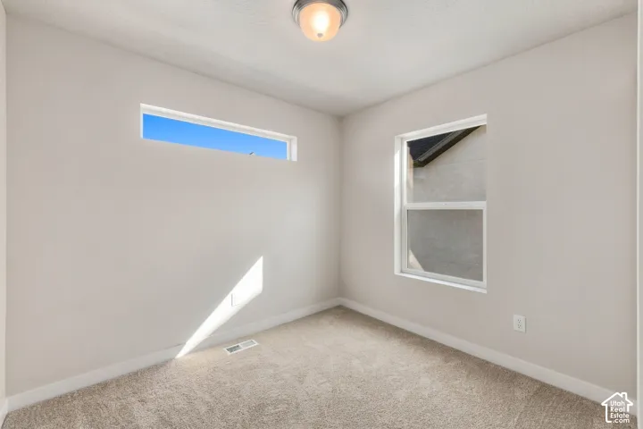 Neutral wall paint with carpet flooring, featuring a rectangular window and an additional transom window