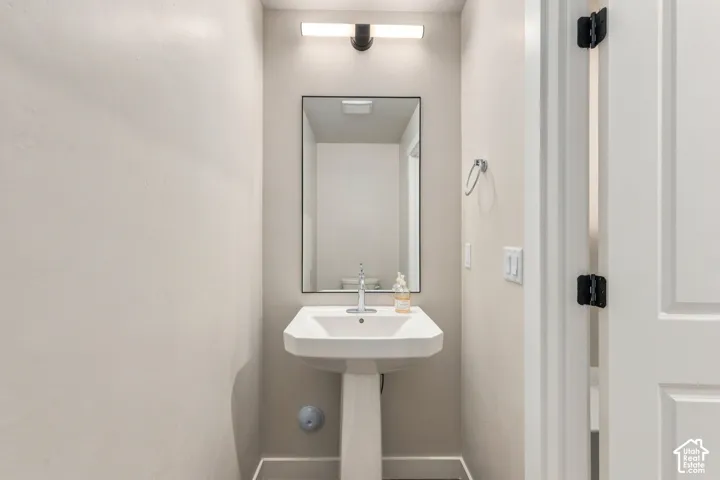 Pedestal sink with chrome faucet, framed mirror, and contemporary vanity lighting fixture