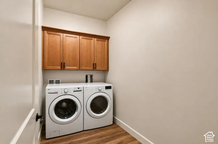 Wood-finish flooring with light-toned walls, featuring wood-finish cabinetry with dark hardware