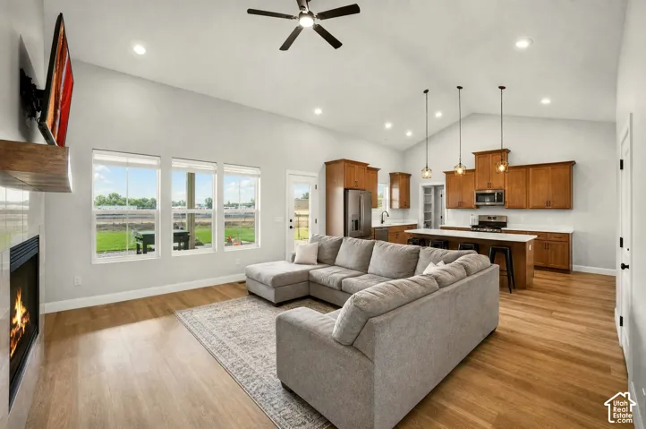 Vaulted ceilings with recessed lighting, wood-finish flooring, a built-in fireplace, a kitchen island with pendant lighting, and abundant natural light