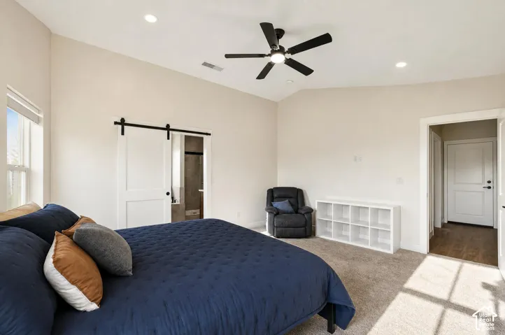 Vaulted ceiling, recessed lighting, ceiling fan, carpet flooring, and a sliding barn door