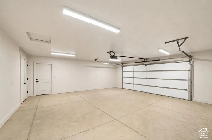 Spacious garage featuring a sectional overhead door, concrete flooring, and multiple ceiling-mounted linear light fixtures