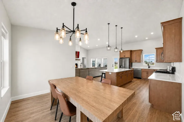 Open-concept kitchen and dining area featuring wood-finish flooring, recessed lighting, and a contemporary chandelier