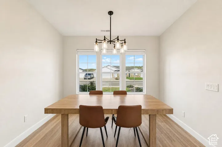 Recessed windows with roller shades, wood-finish flooring, and a contemporary chandelier