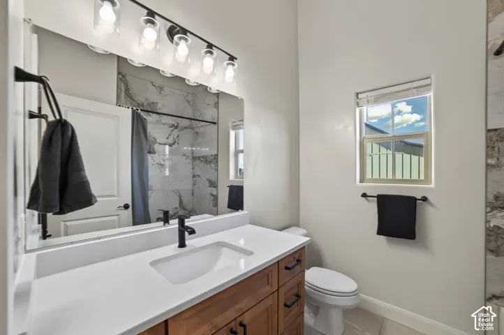 Wood-finish vanity with a white countertop and integrated sink, matte black faucet, and large wall-mounted mirror