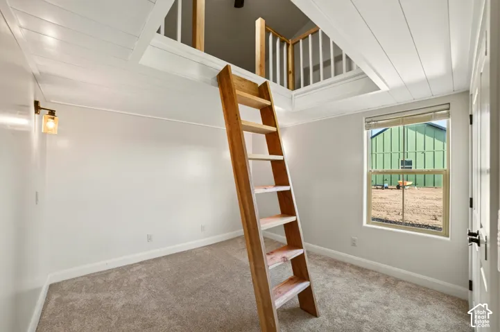 Loft access via an exposed wood ladder, complemented by a horizontal plank ceiling and wall-mounted light fixture