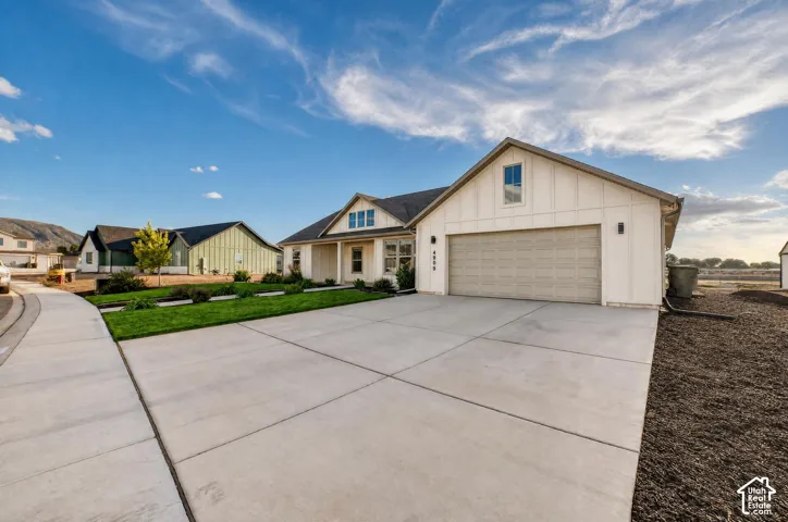 Modern farmhouse exterior with white board and batten siding, attached garage, concrete driveway, and front lawn