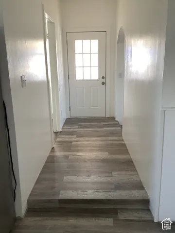 Entryway featuring a white paneled door with glass inserts, wood-finish flooring, and a white arched doorway