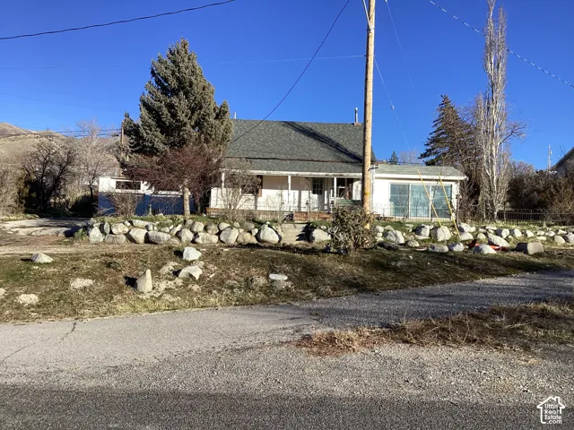 Property featuring a pitched roof, front porch, and rock retaining wall