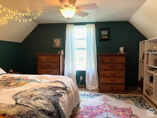 Room featuring a ceiling fan with integrated lighting, a window with drapery, and a built-in shelving unit