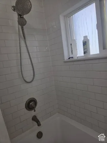 White subway tile surround with a multi-function shower head, bronze-finish fixtures, and integrated bathtub