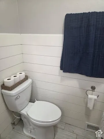 White shiplap wall paneling and a modern toilet