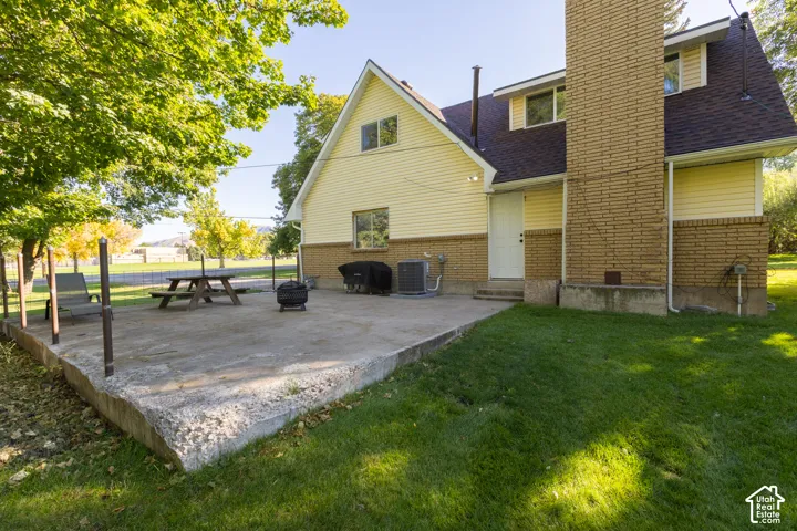 Expansive concrete patio with direct exterior access, featuring a brick chimney and mature trees