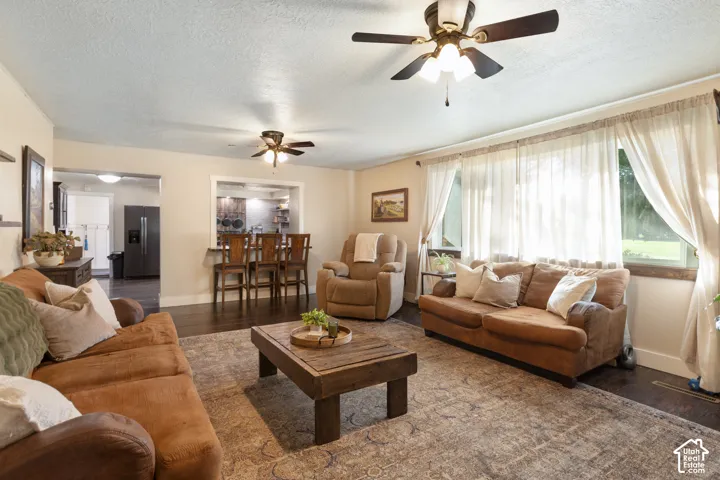 Dark wood-finish flooring, recessed ceiling lighting, ceiling fans, and an open pass-through to a bar seating area