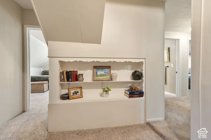 Built-in shelving unit with decorative trim, carpeted flooring, and white painted walls