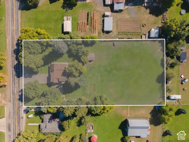 Expansive property featuring a residence, detached outbuilding, mature trees, a driveway, and a substantial open lawn area