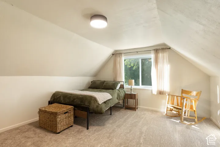 Sloped ceilings, neutral wall tones, flush mount lighting, single window, and carpeted flooring