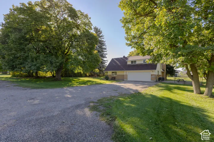 Gravel driveway with extensive green lawn surrounding the property