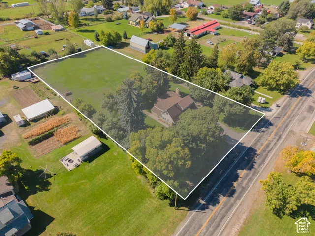 Expansive property featuring a residential structure, mature trees, manicured lawns, and substantial open land