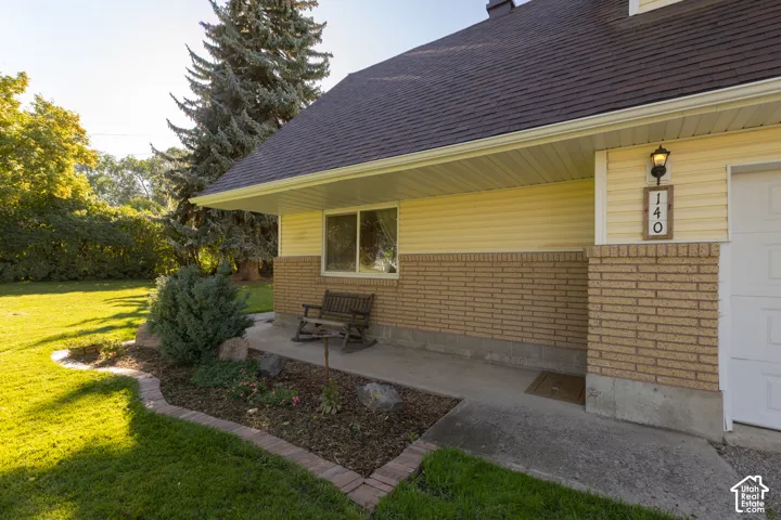 Exterior featuring brick and siding finishes, a covered concrete porch, and established landscaping with mature trees