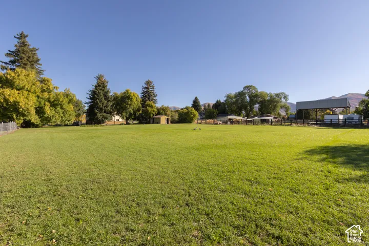 Expansive green lawn with mature trees and a distant mountainous backdrop