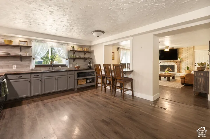 Wood-finish flooring throughout, with gray cabinetry and dark countertops