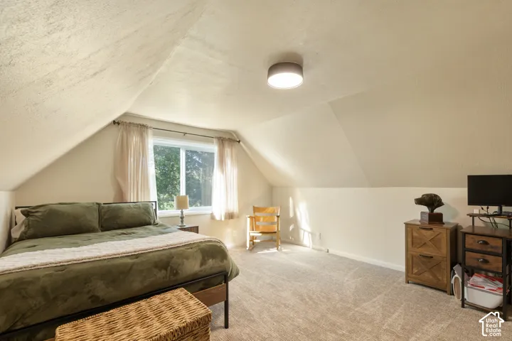 Carpeted room with a window, sloped ceilings, and a flush-mount ceiling light fixture