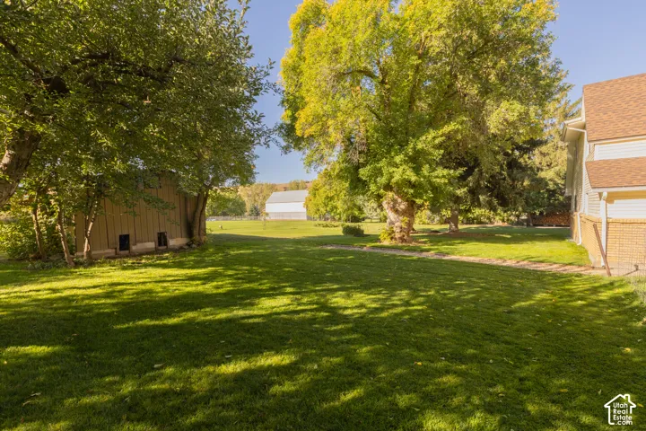 Expansive lawn with mature trees, a detached outbuilding, and a two-story residence with a brick and siding exterior