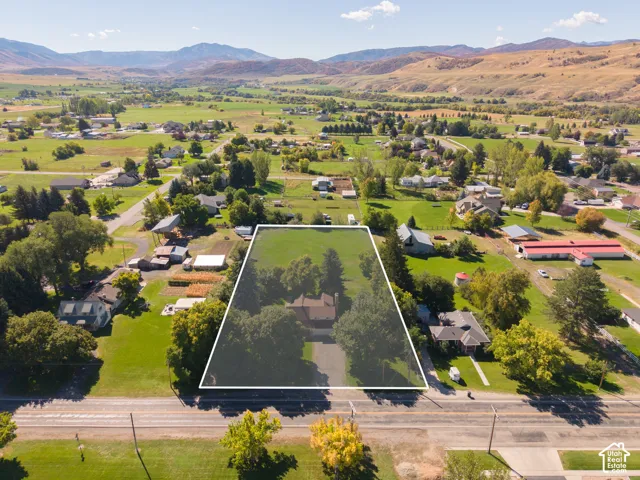 Expansive property with mature trees, green lawn, and mountain scenery