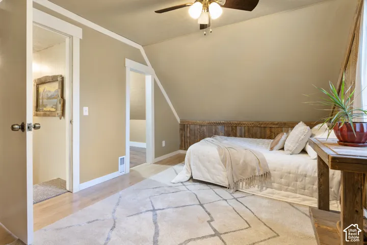 Wood-finish flooring with a sloped ceiling and recessed wood paneling