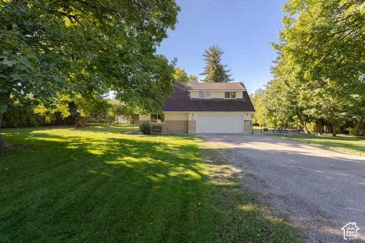 Two-story residence with a dormer window, an attached two-car garage, and a gravel driveway
