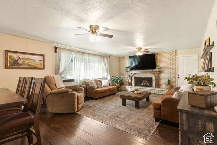 Brick fireplace with a wood mantle, ceiling fans, and expansive windows