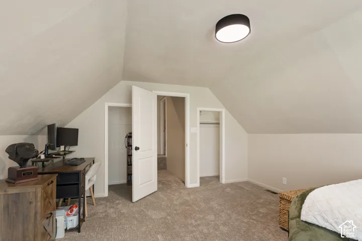 Vaulted ceilings, carpeted flooring, two closet spaces, and an overhead flush-mount light fixture