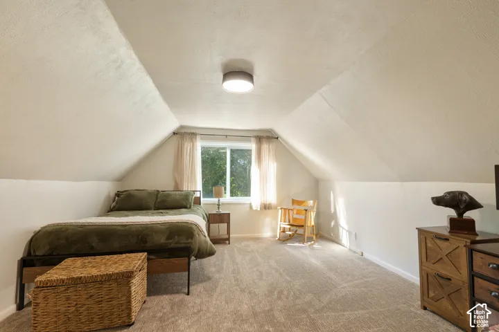 Sloped ceilings with textured finish, carpeted flooring, and a flush-mount ceiling light fixture