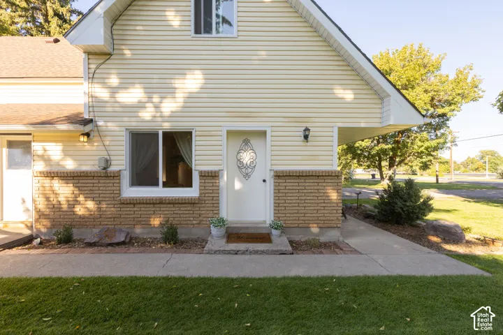 Exterior featuring light-colored siding, a brick accent wall, and a covered entry