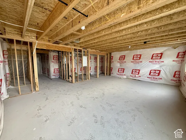 Unfinished basement featuring exposed wood framing, concrete flooring, and Grip-Rite house wrap
