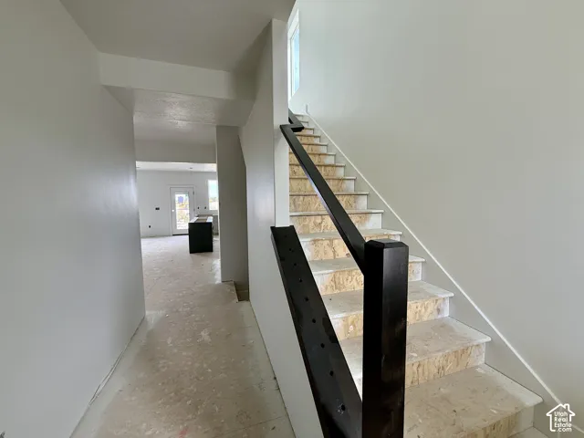 Staircase featuring dark wood handrails and unfinished treads
