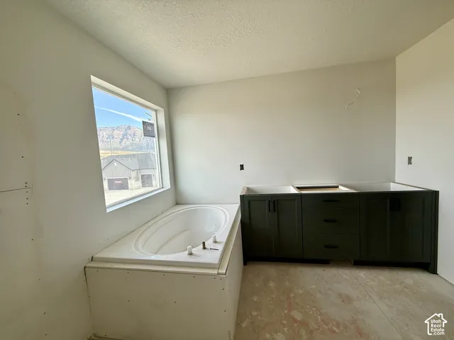 Built-in soaking tub, large window, mountain backdrop, dark wood-finish cabinetry, and matte black hardware