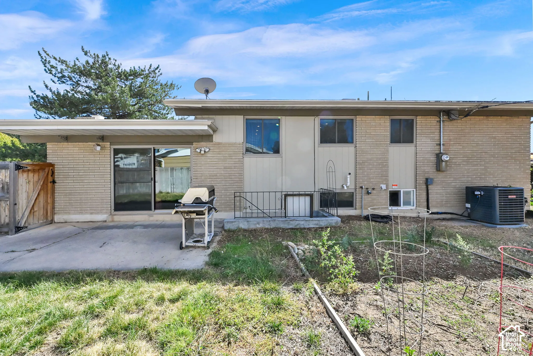 Rear exterior featuring brick siding, sliding glass door access, concrete patio, and a fenced area