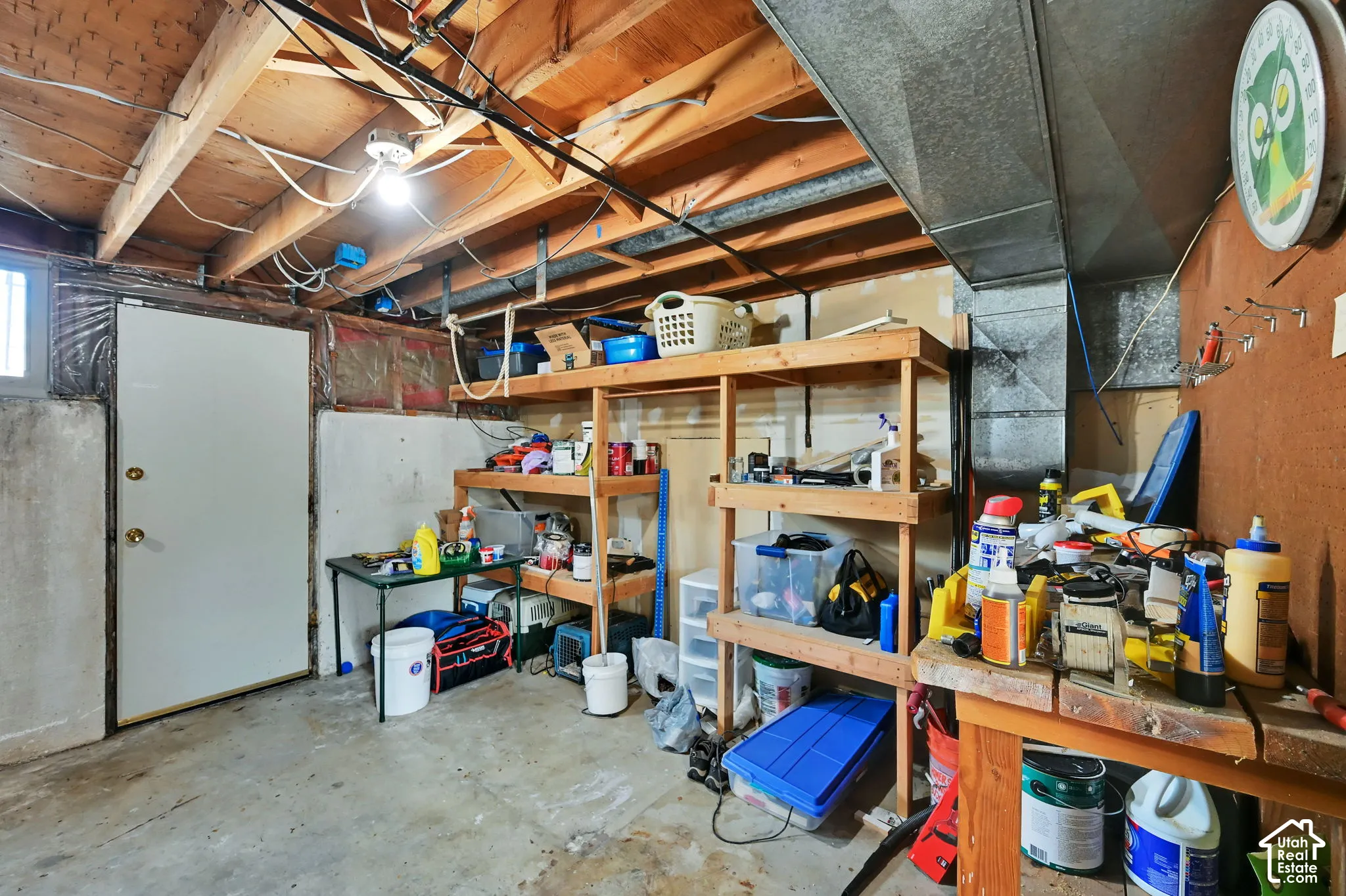 Exposed ceiling joists and ductwork, concrete flooring, and a single light fixture