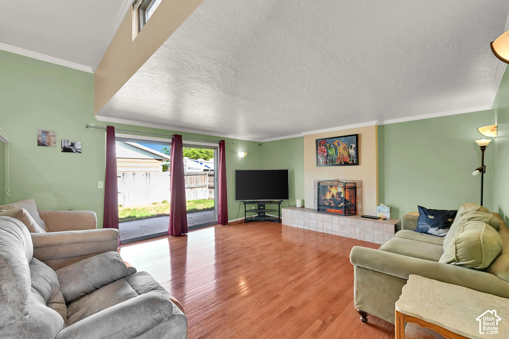Wood-finish flooring, sliding glass door, tile-surround fireplace, vaulted ceiling, and transom window