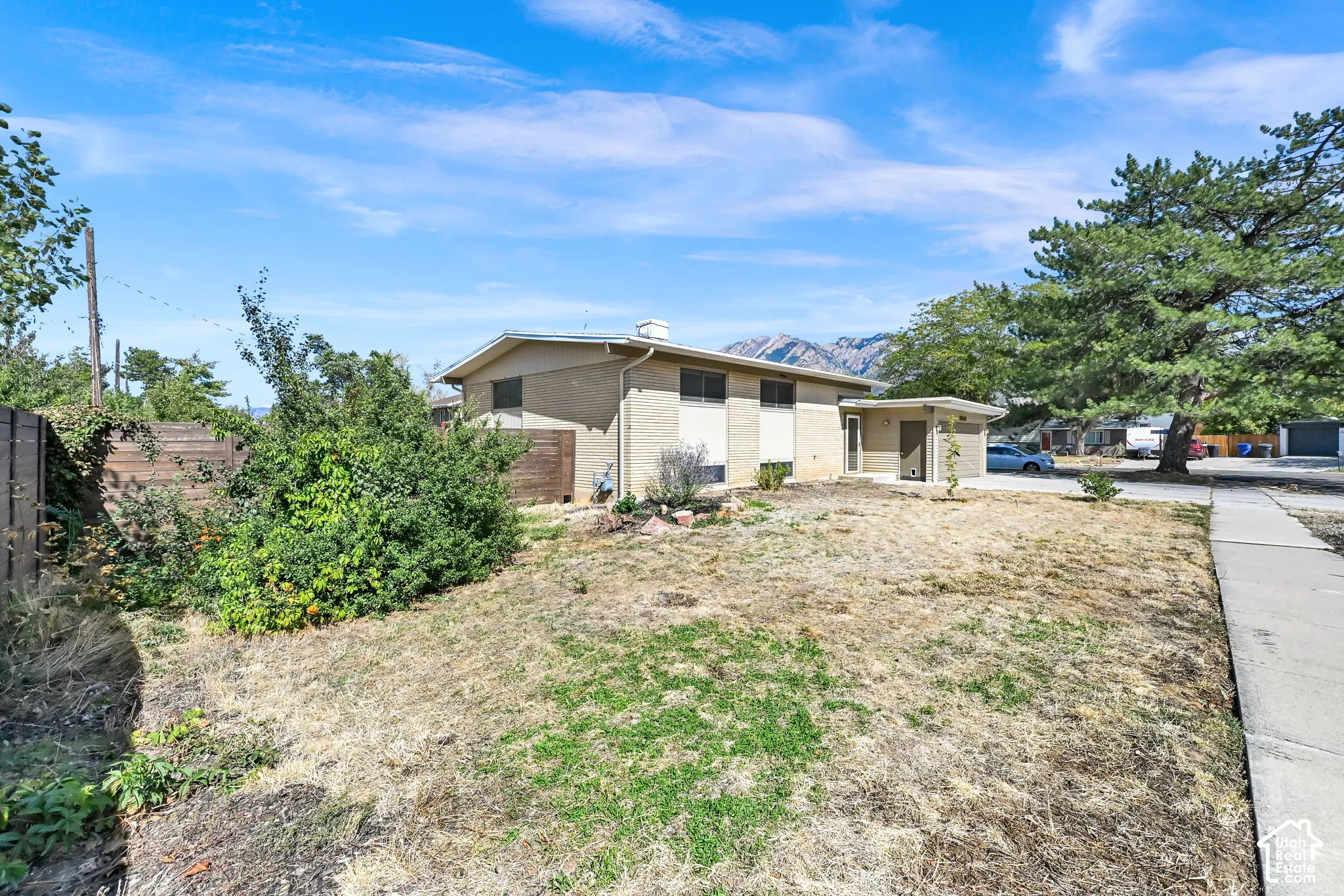 Brick exterior, detached carport, concrete walkway, mature tree, mountain backdrop