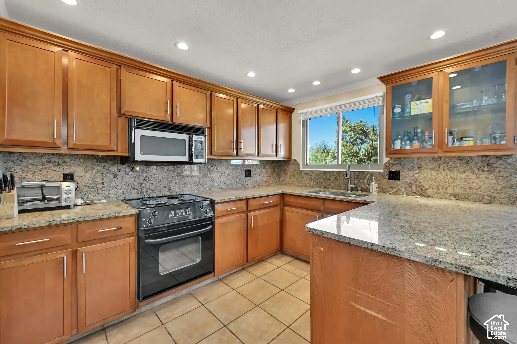 Kitchen featuring wood cabinetry, a built-in microwave, tile flooring, a window above the sink, and an integrated oven