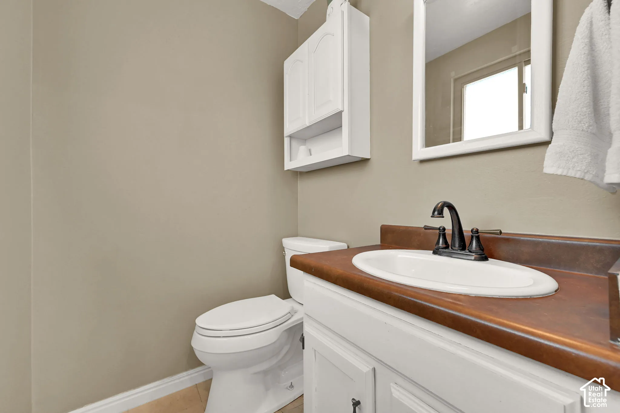 White vanity with integrated sink, bronze-finish faucet, and a brown countertop