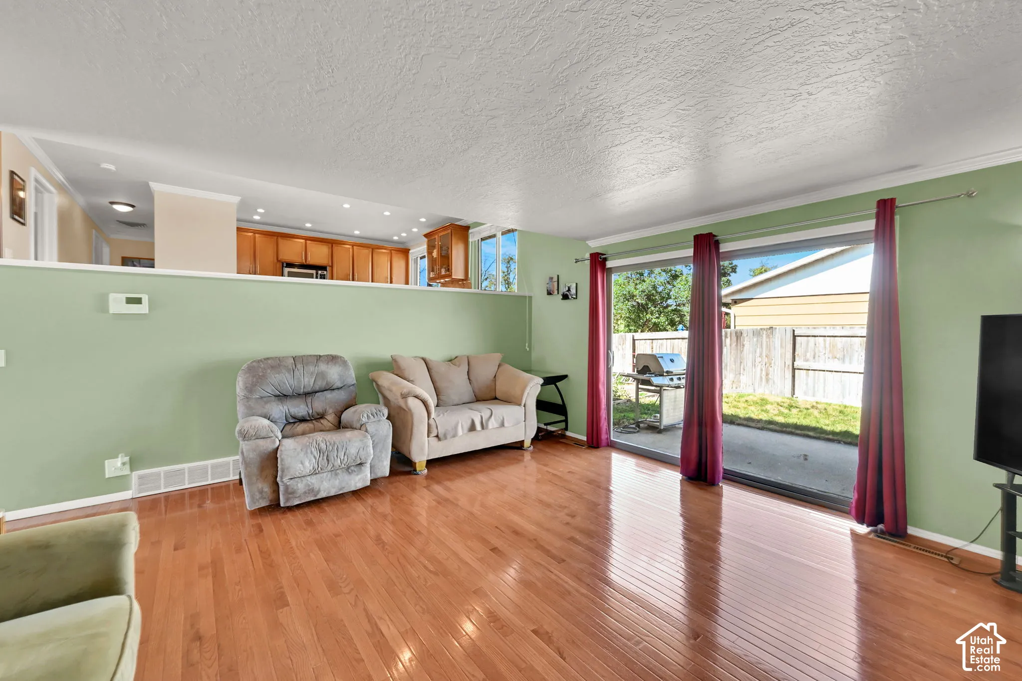 Hardwood flooring, sliding glass door leading to a patio, and a partial wall separating spaces