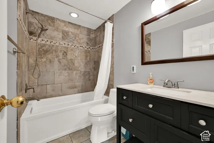 Bathroom featuring a tub and shower combination with tiled surround, a dark wood-finish vanity with a light-toned countertop, and a framed mirror