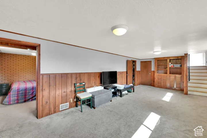 Carpeted living area featuring wood paneling, built-in shelving, and a stairway with carpeted treads