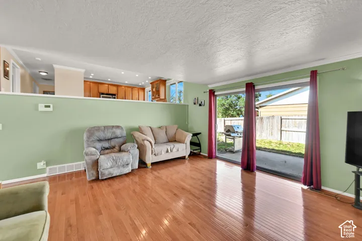 Hardwood flooring, sliding glass door leading to a patio, and a partial wall separating spaces